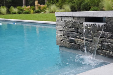 Exemple d'un grand couloir de nage arrière chic rectangle avec un bain bouillonnant et des pavés en pierre naturelle.