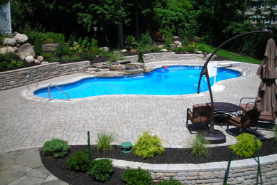 Foto de piscina natural clásica grande a medida en patio trasero con adoquines de hormigón