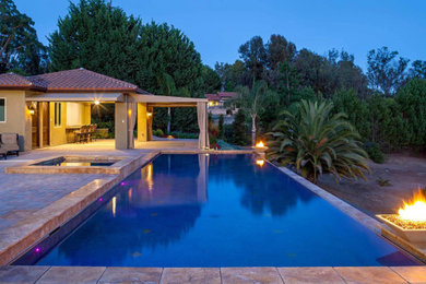 Imagen de casa de la piscina y piscina infinita mediterránea grande rectangular en patio trasero con suelo de baldosas