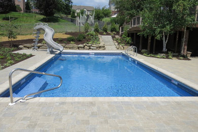 Foto de piscina con tobogán minimalista grande rectangular en patio trasero con suelo de hormigón estampado