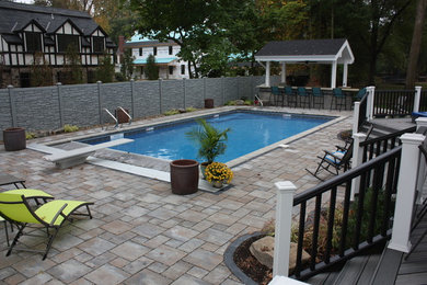 Diseño de piscinas y jacuzzis alargados grandes rectangulares en patio trasero con adoquines de hormigón