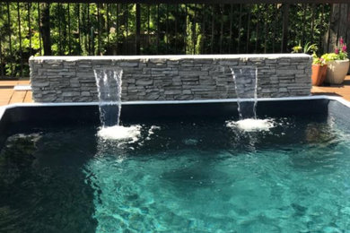 Medium sized modern back rectangular above ground swimming pool in Detroit with decking and a water feature.