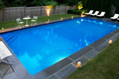 Diseño de piscina mediterránea grande rectangular en patio trasero con adoquines de piedra natural