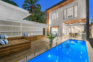 Идея дизайна: спортивный, прямоугольный бассейн среднего размера на заднем дворе в стиле модернизм с домиком у бассейна и покрытием из плитки