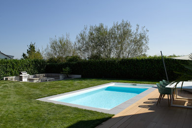Imagen de piscina minimalista de tamaño medio rectangular en patio lateral con losas de hormigón