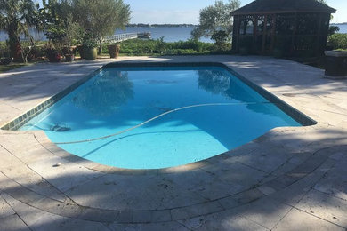 Imagen de piscina alargada tropical de tamaño medio rectangular en patio trasero con adoquines de hormigón