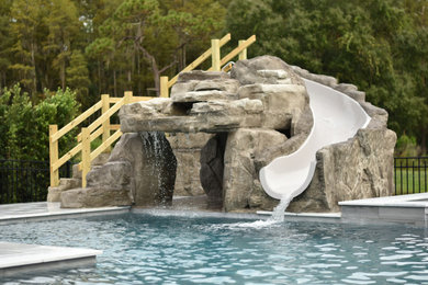 Example of a large trendy backyard stone and custom-shaped water slide design in Tampa