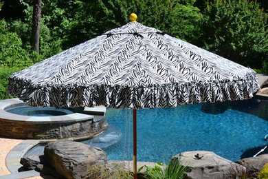 На фото: бассейн среднего размера, произвольной формы на заднем дворе в стиле неоклассика (современная классика) с покрытием из бетонных плит с