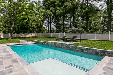 Ejemplo de piscina tradicional de tamaño medio rectangular en patio trasero con adoquines de piedra natural