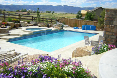 Photo of a large back rectangular natural hot tub in Denver with stamped concrete.