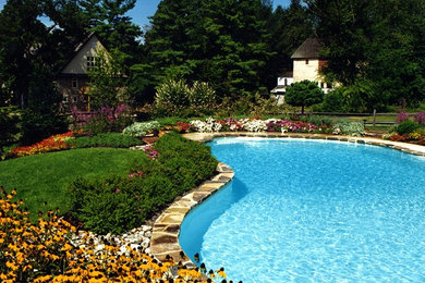 Foto de piscina de estilo de casa de campo grande a medida en patio trasero con adoquines de piedra natural
