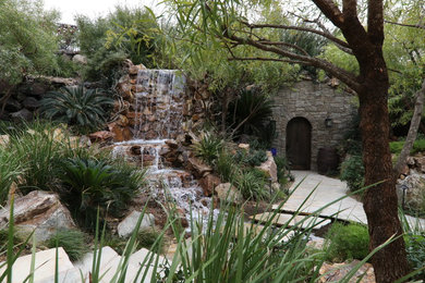 Foto de piscina con fuente natural exótica extra grande a medida en patio trasero con adoquines de piedra natural