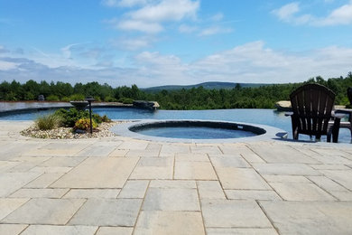 Ejemplo de casa de la piscina y piscina infinita rústica extra grande a medida en patio trasero con adoquines de hormigón