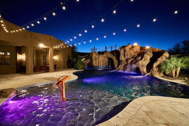 Imagen de piscina con tobogán natural tropical grande a medida en patio trasero con adoquines de piedra natural
