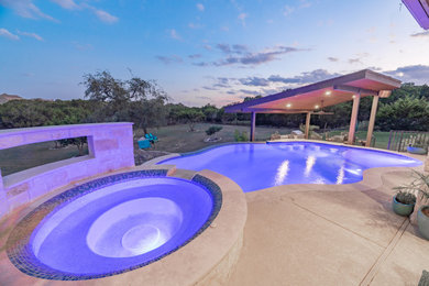 Mid-sized backyard concrete and custom-shaped infinity pool photo in Austin