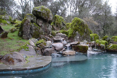 Example of a large mountain style backyard stone and custom-shaped infinity pool fountain design in Sacramento