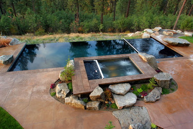 Hot tub - mid-sized contemporary backyard stamped concrete and rectangular infinity hot tub idea in Seattle