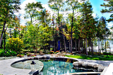 Inspiration för en stor funkis anpassad pool på baksidan av huset, med spabad och naturstensplattor