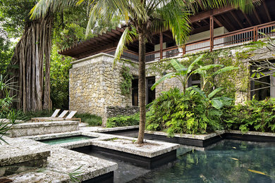 Foto på en stor tropisk pool på baksidan av huset, med spabad och kakelplattor