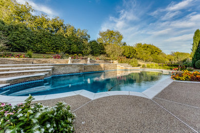 Example of a large classic backyard custom-shaped and concrete lap pool fountain design in Dallas