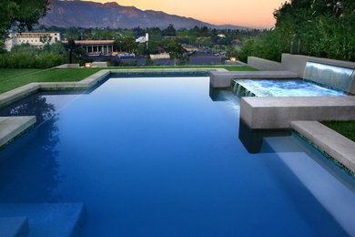 Ejemplo de piscina con fuente infinita minimalista grande rectangular en patio trasero con losas de hormigón