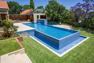 Ejemplo de piscina alargada minimalista de tamaño medio rectangular en patio trasero con adoquines de piedra natural