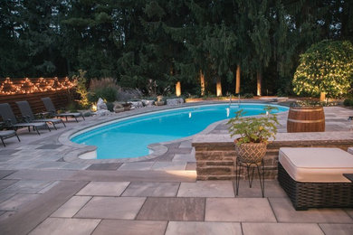 Esempio di una piscina monocorsia minimal rotonda di medie dimensioni e dietro casa con pavimentazioni in pietra naturale e una dépendance a bordo piscina