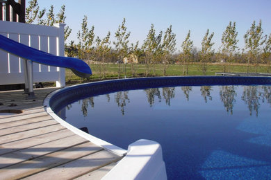 Imagen de piscina elevada grande redondeada en patio trasero con entablado