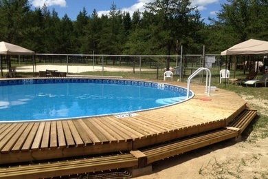Foto de piscina natural de tamaño medio redondeada en patio trasero con entablado