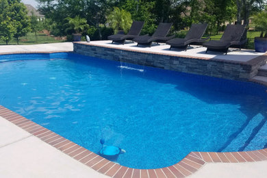 Ejemplo de piscina con fuente alargada tradicional de tamaño medio rectangular en patio trasero con adoquines de hormigón