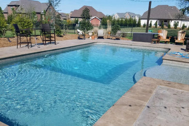 Foto de piscina alargada clásica de tamaño medio rectangular en patio trasero con suelo de hormigón estampado