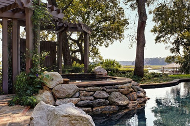 Example of a large classic backyard stone and custom-shaped natural hot tub design in Charleston