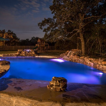Rustic lagoon style pool with a fire pit, water falls and a hot tub