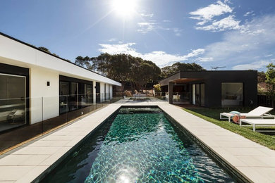 Imagen de casa de la piscina y piscina alargada contemporánea grande rectangular en patio trasero con suelo de baldosas