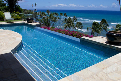 This is an example of a large world-inspired back custom shaped infinity swimming pool in Hawaii with natural stone paving.
