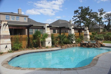 Diseño de piscinas y jacuzzis alargados exóticos de tamaño medio a medida en patio trasero con adoquines de piedra natural