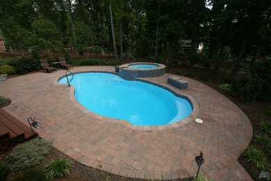 Inspiration for a mid-sized timeless backyard brick and custom-shaped pool remodel in Other