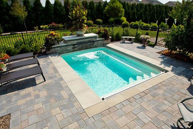 Imagen de piscina con fuente alargada minimalista de tamaño medio rectangular en patio trasero con adoquines de hormigón