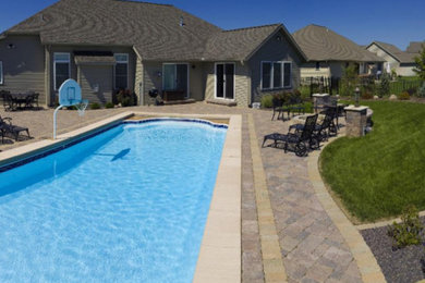 Foto de piscina alargada clásica grande rectangular en patio trasero con adoquines de hormigón