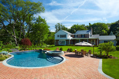 Mid-sized elegant backyard brick and round hot tub photo in New York