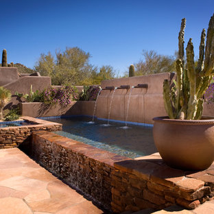 Ejemplo de piscinas y jacuzzis infinitos, de estilo americano, de tamaño medio, rectangulares, en patio trasero, con adoquines de piedra natural