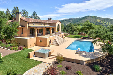 Ejemplo de piscinas y jacuzzis alargados mediterráneos grandes rectangulares en patio trasero con adoquines de hormigón