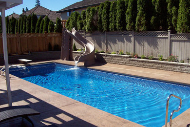 Ejemplo de piscina con tobogán clásica de tamaño medio rectangular en patio lateral con suelo de hormigón estampado