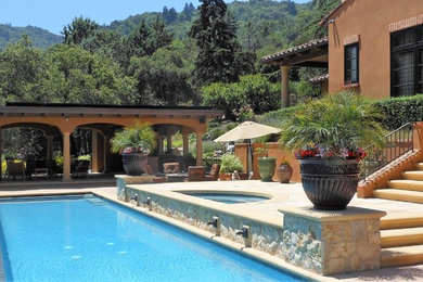 Tuscan backyard concrete paver and rectangular infinity pool house photo