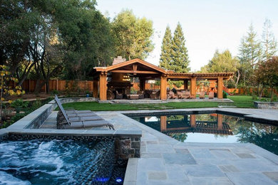 Photo of an expansive contemporary back custom shaped lengths hot tub in San Francisco with natural stone paving.