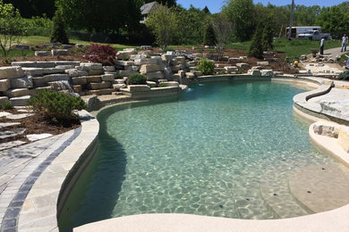 Ispirazione per un'ampia piscina naturale moderna personalizzata dietro casa con fontane e pavimentazioni in pietra naturale