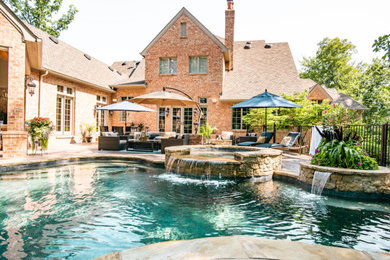 Elegant backyard stamped concrete and custom-shaped natural pool fountain photo in St Louis