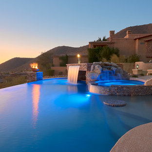 Esempio di una grande piscina a sfioro infinito contemporanea personalizzata dietro casa con fontane e pedane