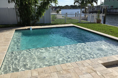 Ejemplo de piscina natural minimalista de tamaño medio rectangular en patio trasero con adoquines de piedra natural