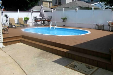 Modelo de piscina elevada tradicional de tamaño medio redondeada en patio trasero con entablado